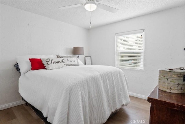 bedroom featuring hardwood / wood-style flooring, ceiling fan, and a textured ceiling