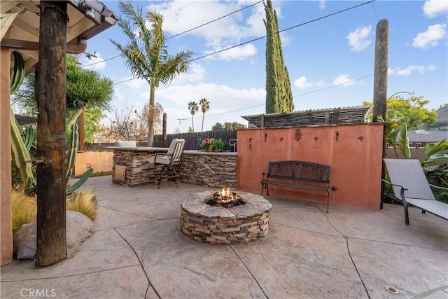 view of patio with an outdoor kitchen, an outdoor bar, and a fire pit