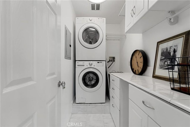 laundry room featuring cabinets, stacked washing maching and dryer, and electric panel