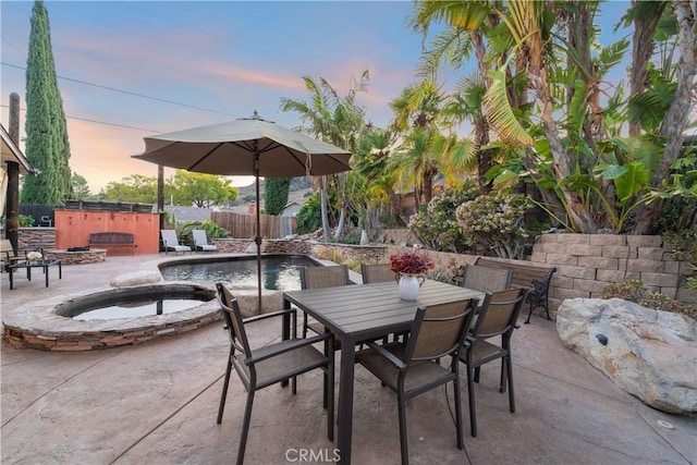 patio terrace at dusk featuring a pool with hot tub