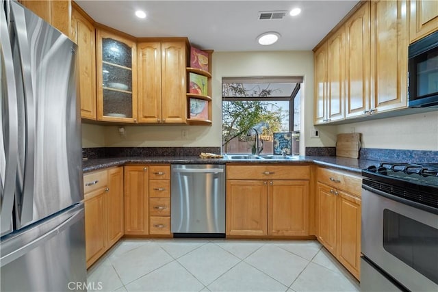 kitchen featuring stainless steel appliances, sink, light tile patterned floors, and dark stone counters