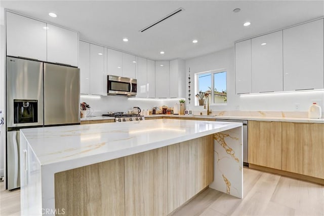 kitchen featuring stainless steel appliances, recessed lighting, modern cabinets, and a center island