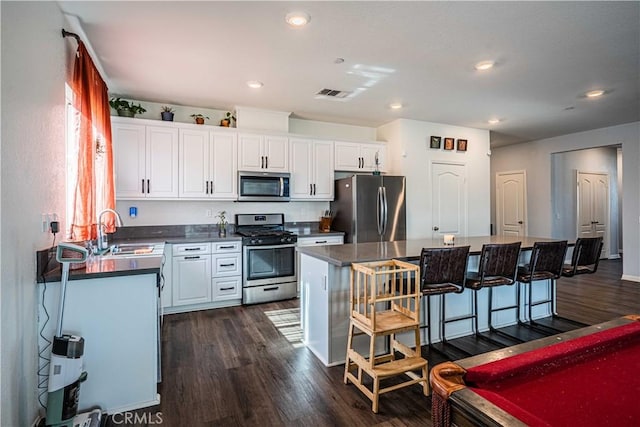 kitchen featuring stainless steel appliances, sink, white cabinets, and a breakfast bar