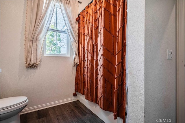 bathroom featuring wood-type flooring, a shower with shower curtain, and toilet