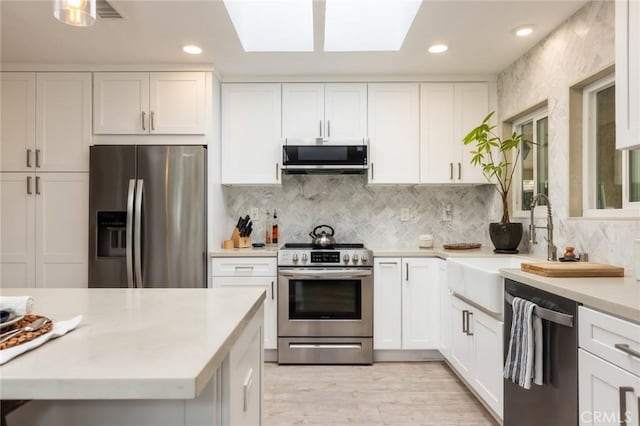 kitchen featuring white cabinetry, sink, backsplash, and appliances with stainless steel finishes