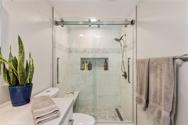 bathroom featuring vanity, a shower with shower door, and toilet