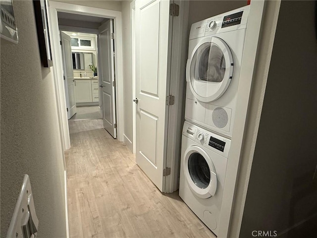 laundry room featuring stacked washer and dryer and light hardwood / wood-style floors