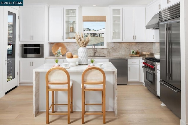 kitchen with a kitchen bar, sink, white cabinets, and premium appliances