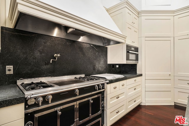 kitchen featuring dark wood-type flooring, custom range hood, oven, decorative backsplash, and cream cabinetry