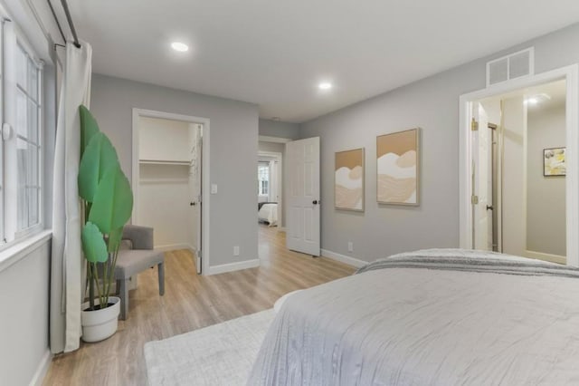 bedroom with a spacious closet and light hardwood / wood-style floors