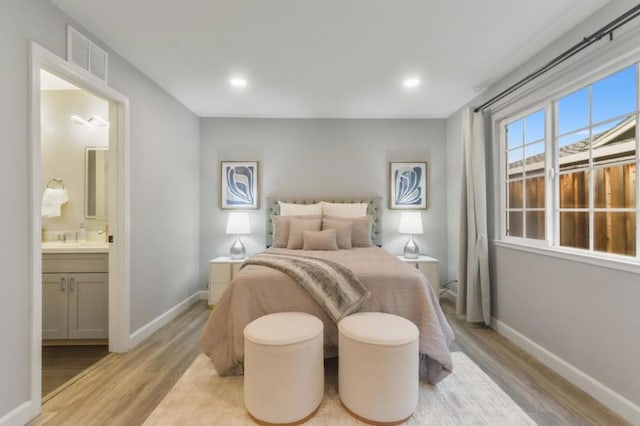 bedroom with connected bathroom and light hardwood / wood-style flooring