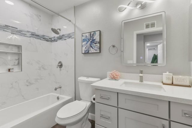 full bathroom with vanity, tiled shower / bath, and toilet