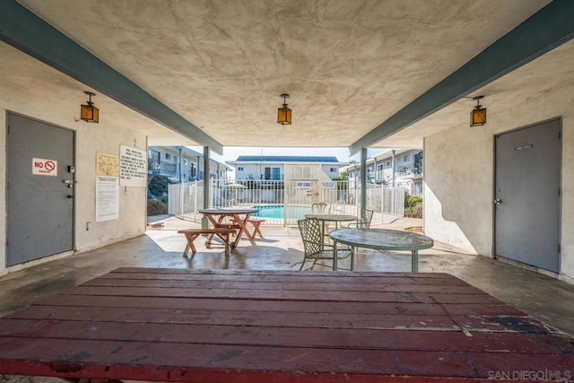 wooden terrace featuring a community pool and a patio