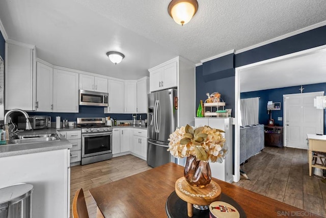 kitchen featuring sink, light wood-type flooring, white cabinets, and appliances with stainless steel finishes