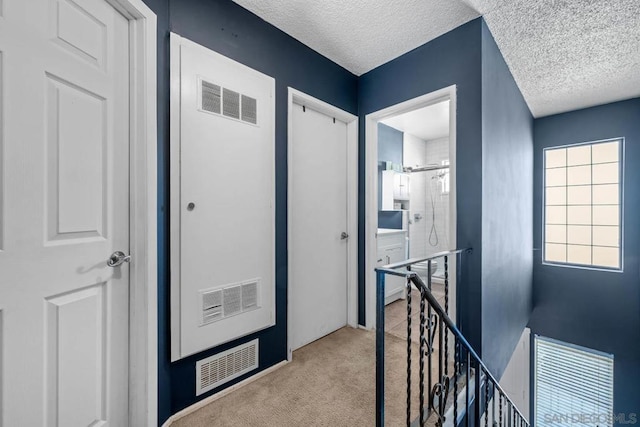 corridor featuring light carpet and a textured ceiling