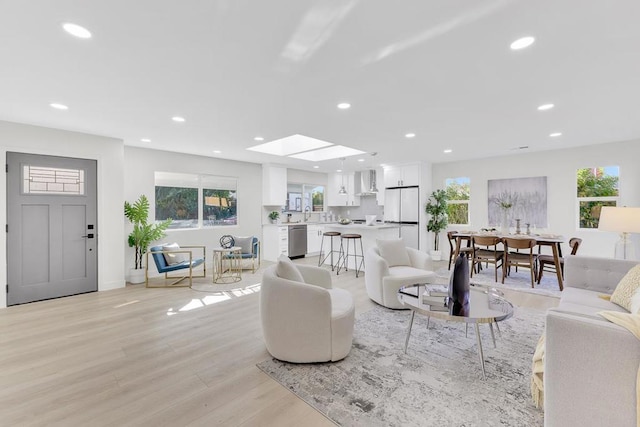 living room with a skylight, sink, and light wood-type flooring