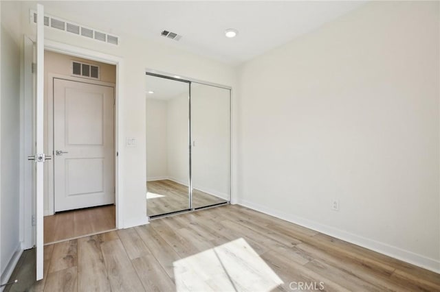 unfurnished bedroom with light wood-type flooring and a closet