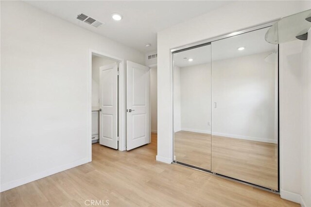 unfurnished bedroom with light hardwood / wood-style flooring and a closet