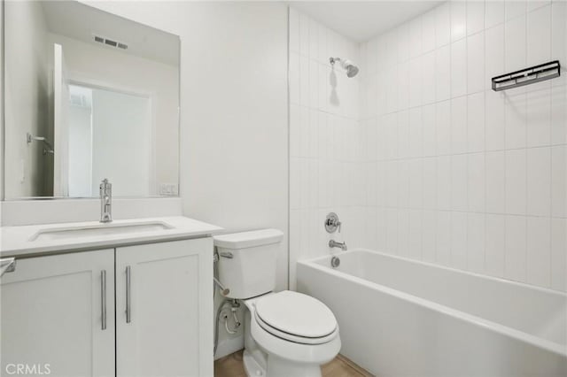 full bathroom with tiled shower / bath, vanity, and toilet