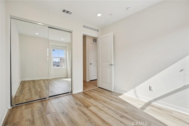 unfurnished bedroom featuring light hardwood / wood-style floors and a closet