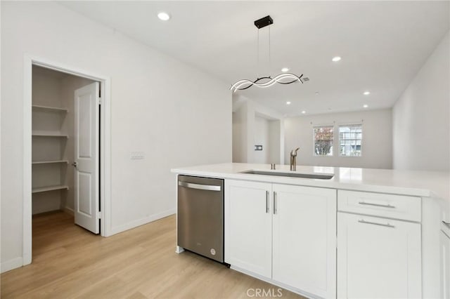 kitchen featuring sink, dishwasher, hanging light fixtures, white cabinets, and light wood-type flooring