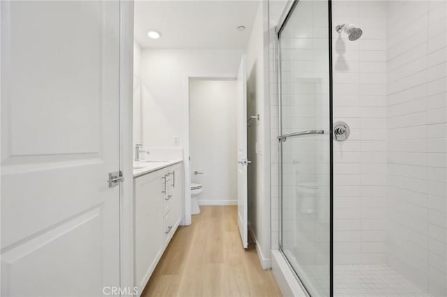 bathroom featuring vanity, an enclosed shower, hardwood / wood-style flooring, and toilet