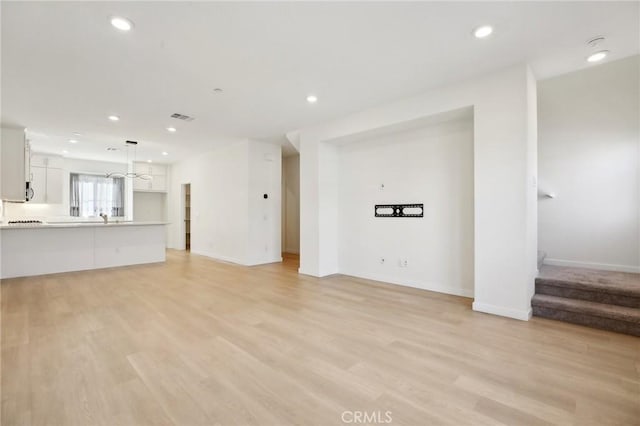 unfurnished living room featuring sink and light wood-type flooring