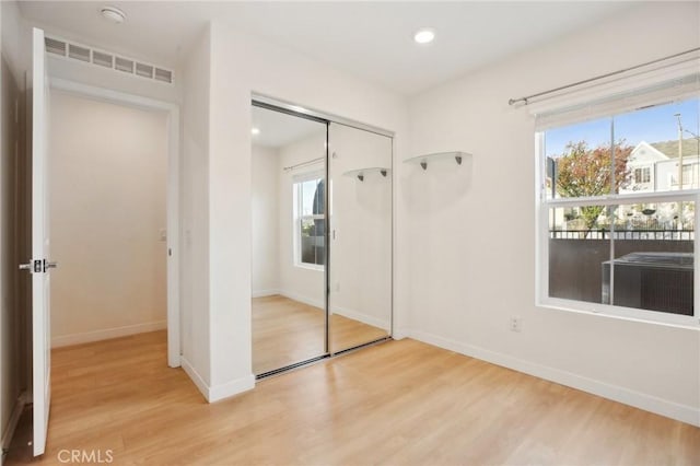 unfurnished bedroom with light wood-type flooring and a closet