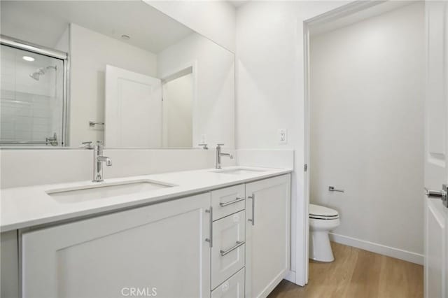 bathroom with hardwood / wood-style flooring, vanity, walk in shower, and toilet