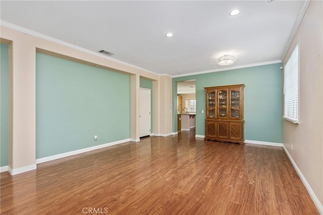 empty room with hardwood / wood-style flooring and crown molding