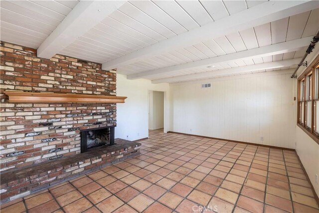 unfurnished living room featuring beamed ceiling, light tile patterned flooring, a brick fireplace, and wood walls