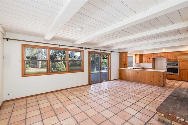 kitchen featuring double oven, light tile patterned floors, beam ceiling, and kitchen peninsula