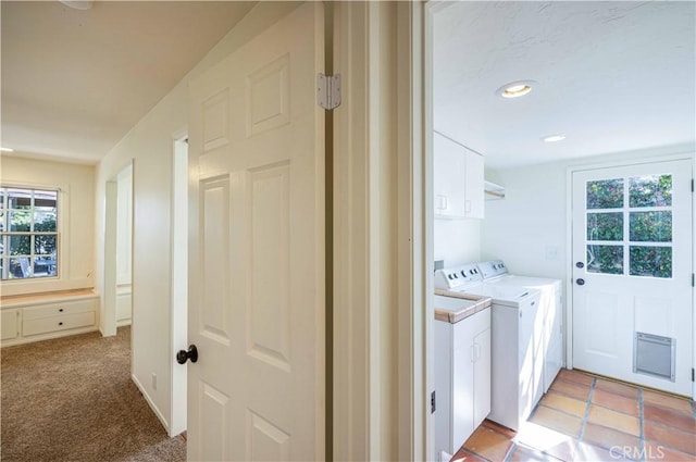 clothes washing area featuring cabinets, light colored carpet, and washing machine and clothes dryer