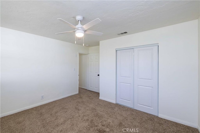 unfurnished bedroom featuring ceiling fan, carpet floors, a closet, and a textured ceiling