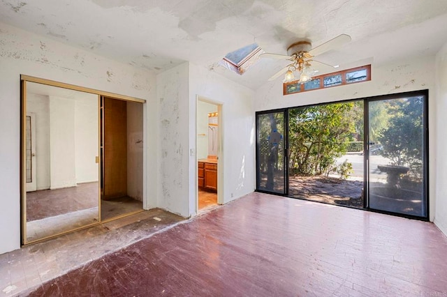 unfurnished bedroom featuring lofted ceiling with skylight, connected bathroom, access to exterior, ceiling fan, and a closet