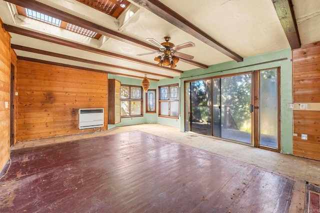 unfurnished living room featuring heating unit, beam ceiling, and wooden walls