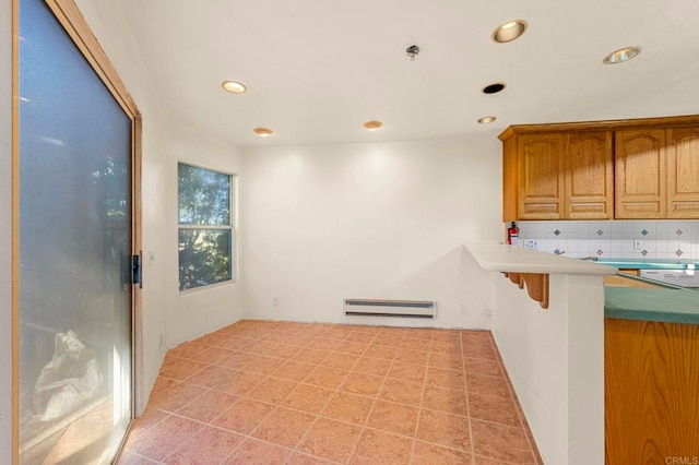 kitchen featuring a baseboard radiator, a breakfast bar area, and backsplash