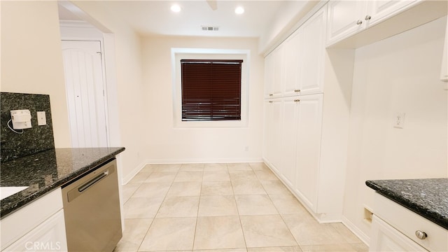 kitchen featuring white cabinetry, stainless steel dishwasher, dark stone counters, and light tile patterned flooring