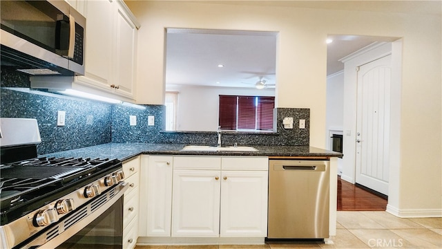 kitchen featuring sink, dark stone counters, stainless steel appliances, decorative backsplash, and white cabinets