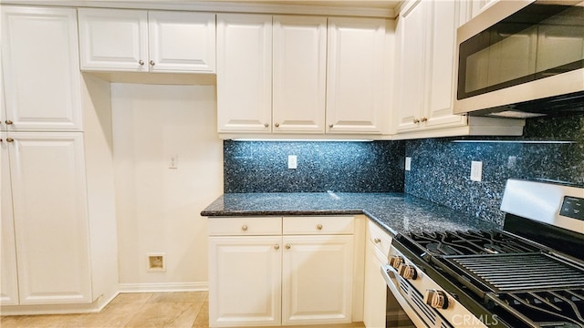 kitchen with white cabinetry, appliances with stainless steel finishes, decorative backsplash, and dark stone counters