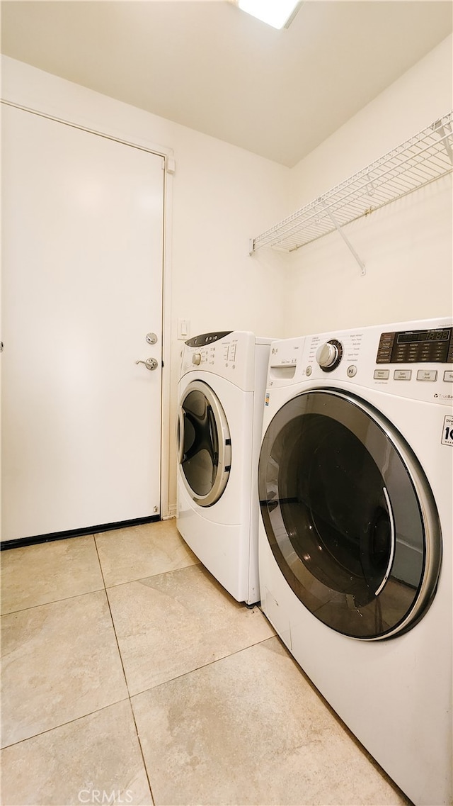 laundry area with washing machine and dryer and light tile patterned floors