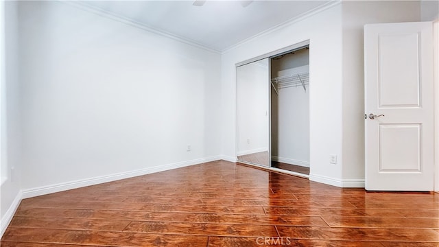 unfurnished bedroom with ornamental molding, hardwood / wood-style floors, ceiling fan, and a closet