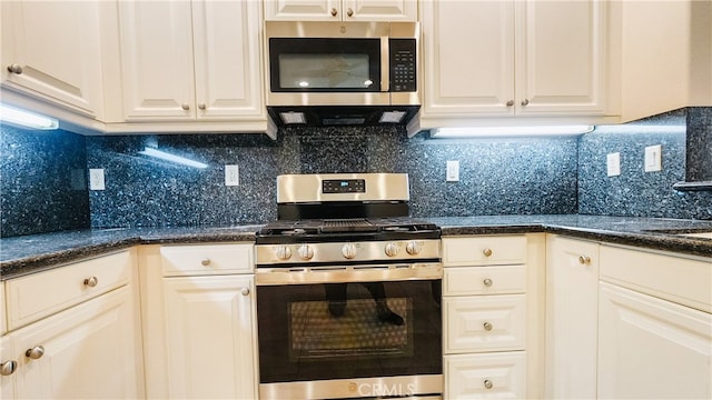 kitchen with dark stone countertops, decorative backsplash, stainless steel appliances, and white cabinets