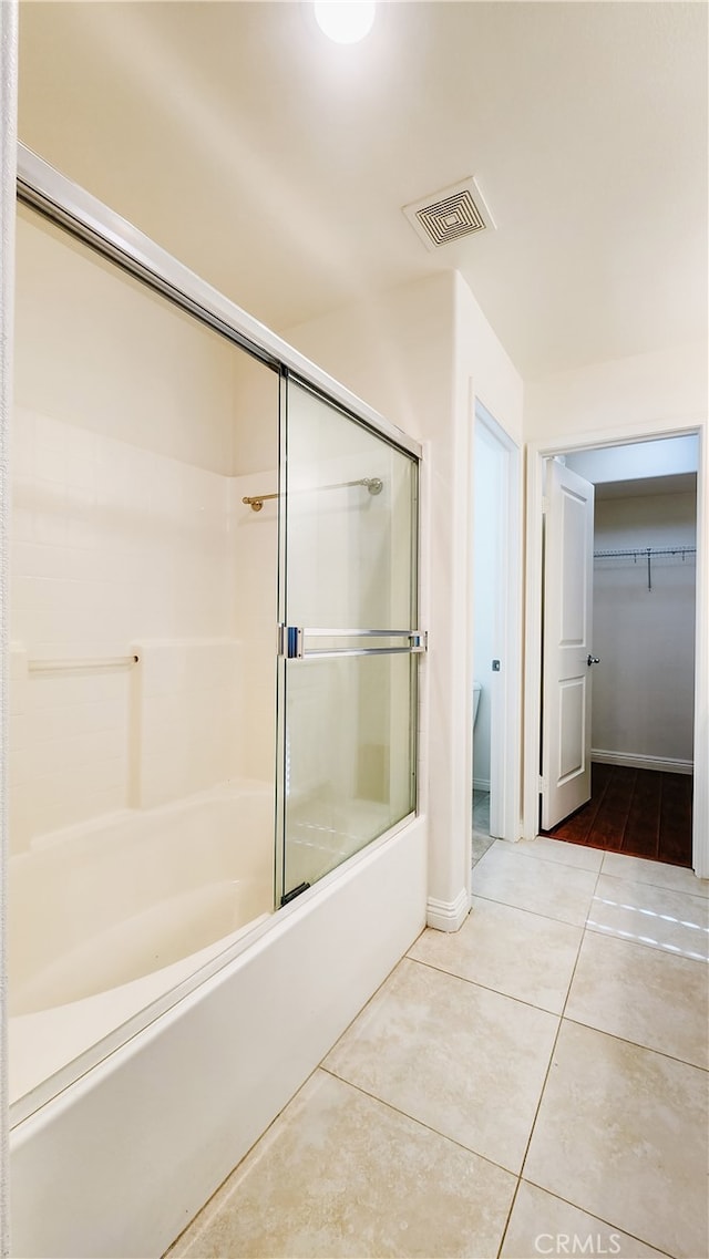 bathroom with bath / shower combo with glass door and tile patterned floors