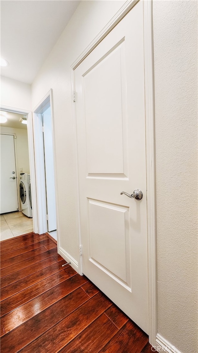 hallway with separate washer and dryer and dark hardwood / wood-style floors