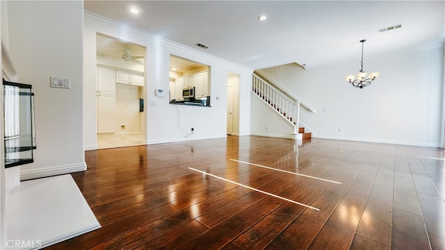 unfurnished living room with crown molding, dark hardwood / wood-style floors, and a chandelier