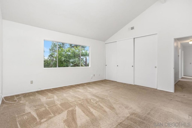 unfurnished bedroom featuring carpet flooring, high vaulted ceiling, and a closet