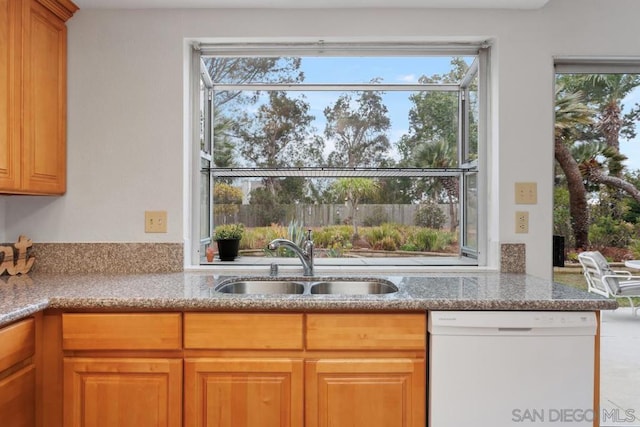 kitchen with dishwasher, sink, and light stone counters