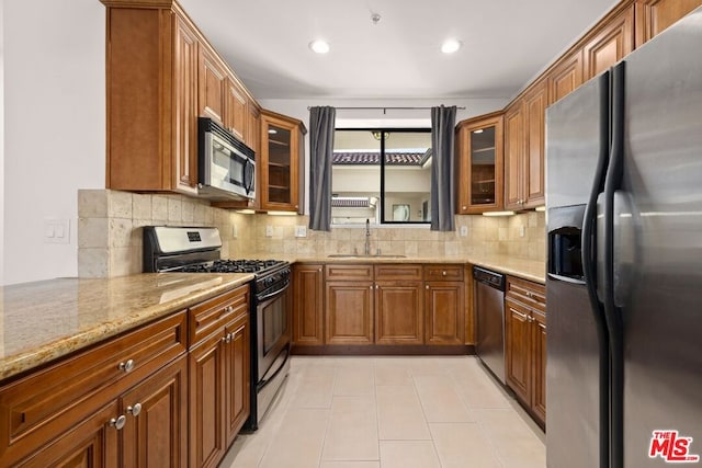 kitchen featuring sink, light tile patterned floors, appliances with stainless steel finishes, light stone countertops, and decorative backsplash