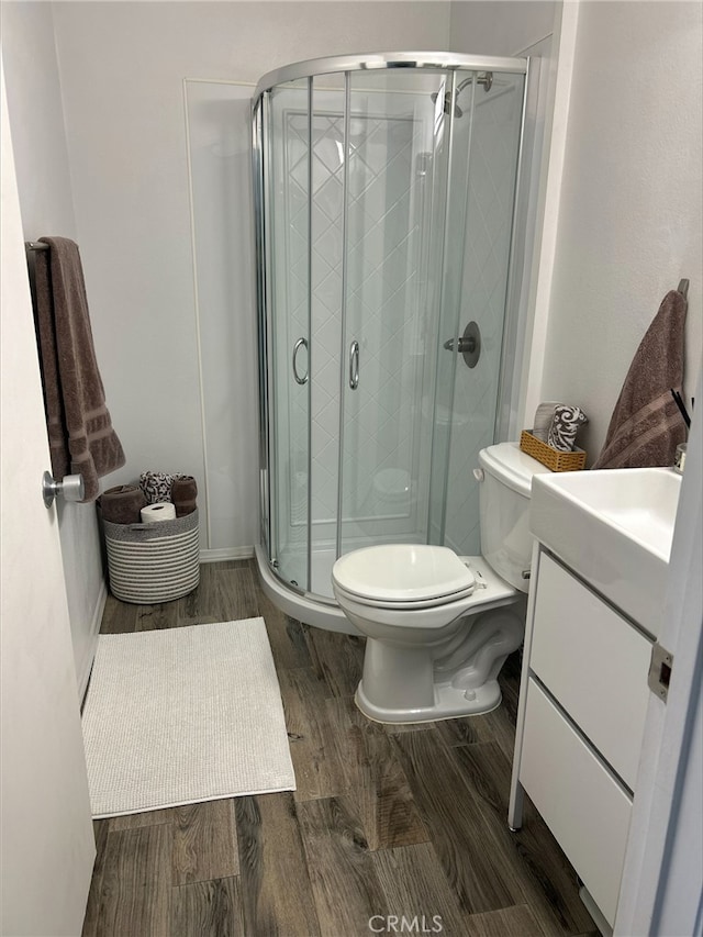 bathroom featuring vanity, wood-type flooring, toilet, and walk in shower